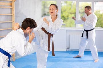 Fototapeta na wymiar Woman and man in kimono sparring together in gym during karate training