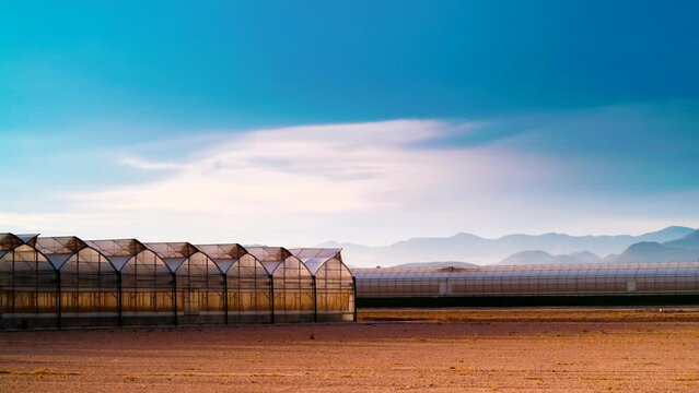 Time lapse of clouds moving in the evening sunset time over coast landscape with commercial greenhouses. Industrial agriculture. Murcia region, Spain.