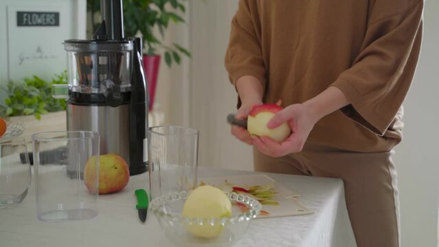 Woman pealing apples and other fruit for the juicer , making juice from raw food 