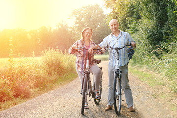 elderly, mature man and woman with bicycles, happy couple rides together in park, bicycle tour of...