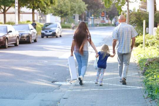 blurred image, man and woman with child, happy family together walks along city street, concept of family serene happiness, cherishing life's moments, back view, urban landscape
