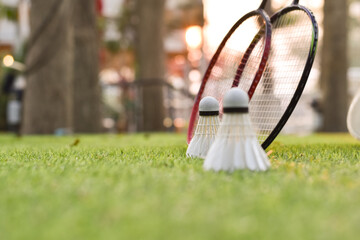 Badminton sport equipments, rackets and white cream shuttlecocks, on green grass lawn, blurred...