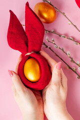 Woman holds a shiny Easter golden egg in her hand.