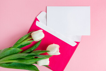 Envelope with invitation to holiday and  bouquet of tulips on pink background.