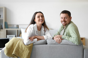 Fototapeta na wymiar Happy young couple sitting on sofa at home
