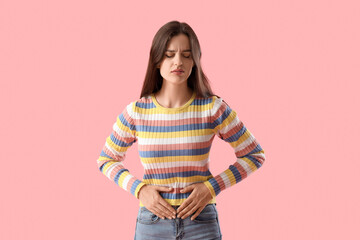 Young woman suffering from stomach ache on pink background