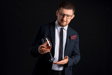 Young sommelier with glass of wine on black background