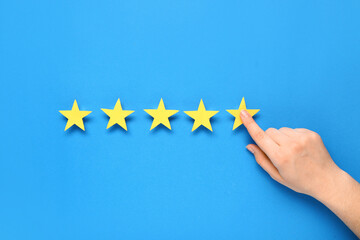 Female hand and five stars rating on blue background. Customer experience concept