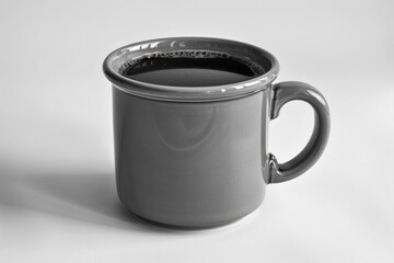 Monochrome gray pottery mug filled with black coffee on a white background.