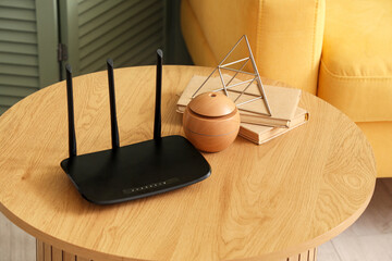 Modern wi-fi router with books on table in living room, closeup