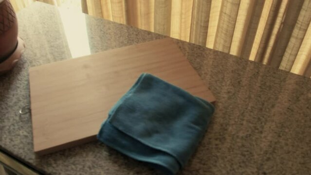 March 3, 2024 - Toronto, Ontario Canada. Examining a wooden cutting board and kitchen rag on a countertop.