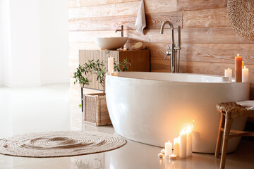 Interior of bathroom with bathtub, sink and burning candles