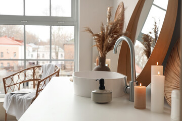 Burning candles with soap near sink in bathroom