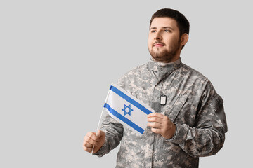 Male Jewish soldier with flag of Israel on light background