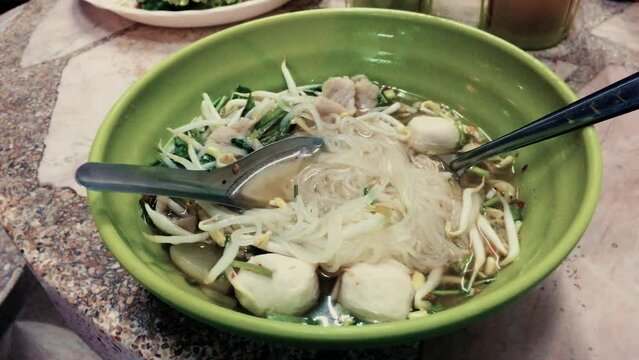 February 14, 2022 - Jomtien Beach, Chonburi Thailand. Eating a bowl of Thai rice noodles with pork at a street food cart.