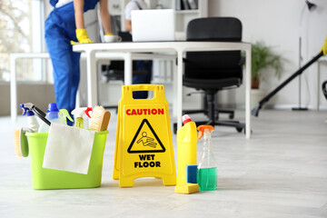 Cleaning supplies with caution sign in office, closeup