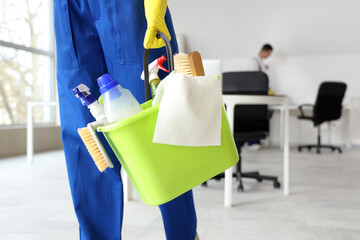 Female janitor with bucket of cleaning supplies in office, closeup - obrazy, fototapety, plakaty