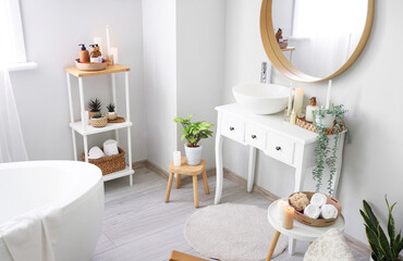 Interior of light bathroom with burning candles and sink