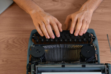 Male author typing on vintage typewriter on table, closeup