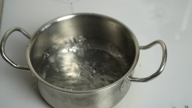 A pot fills with water on an electric stove. Captivating cooking moment, perfect for culinary content.