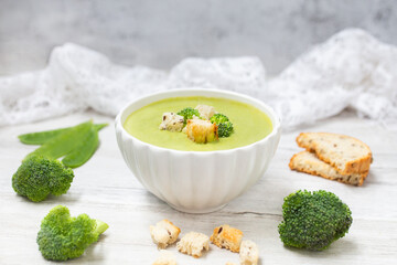 Broccoli cream soup on white wooden background. 