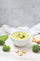 Broccoli cream soup on white wooden background. 