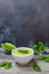 Homemade spinach cream soup in white bowl with bread. 