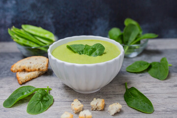 Homemade spinach cream soup in white bowl with bread. 