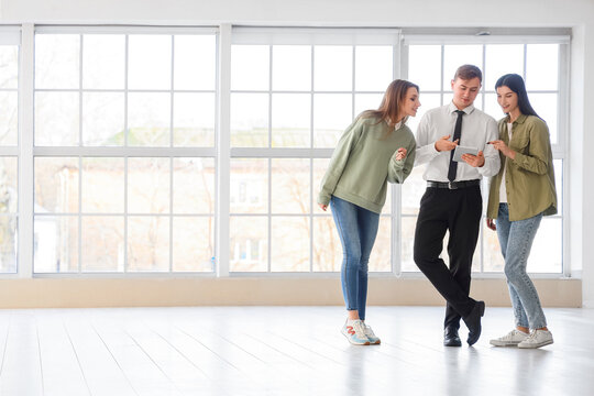 Real estate agent with lesbian couple using tablet computer in new house - Powered by Adobe