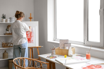 Female artist with painting in workshop, back view