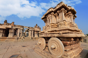 Ancient stone chariot with intricate carvings and medieval ruins at Vijaya Vittala temple at Hampi, Karnataka, India.