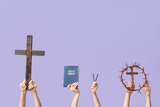 Female hands with wooden crosses, Holy Bible, nails and crown of thorns on lilac background. Good Friday concept