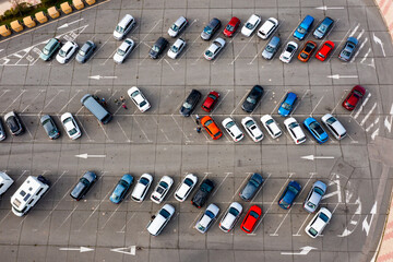Paved outdoor parking with white road markings, infrastructure filled with cars, view from copter.