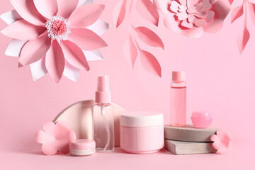 Obraz na płótnie Canvas Facial cosmetic products composition with paper flowers on pink background