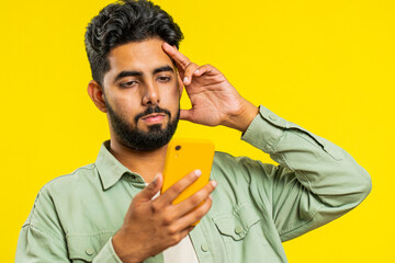 Upset sad Indian man use smartphone typing browsing, play game, loses, surprised by sudden lottery...