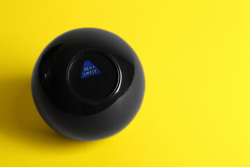 Magic eight ball with prediction Very Likely on yellow background, above view. Space for text