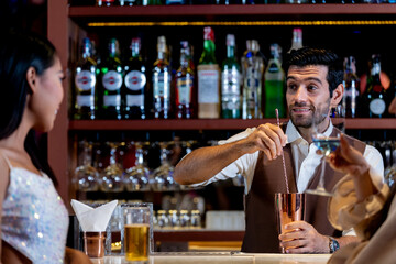 two girls in sexy dress are drinking and dancing at bar. Dance party with group people dancing . Women and men have fun and drinking martini cocktail in night club.