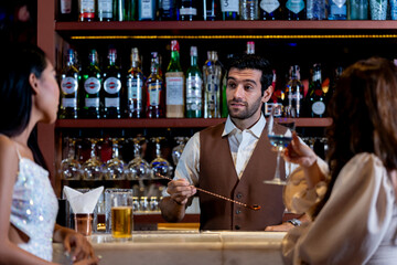 two girls in sexy dress are drinking and dancing at bar. Dance party with group people dancing . Women and men have fun and drinking martini cocktail in night club.