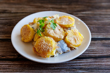 Finnish Food: Casserole made from potatoes and herring close up on plate. Horizontal view from above