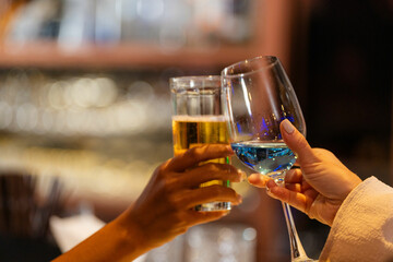 close up glasses of clinking glasses of champagne with lighting. Dinner party with drinking of champagne. hands holding clear glass with alcohol in yellow shine reflect.
