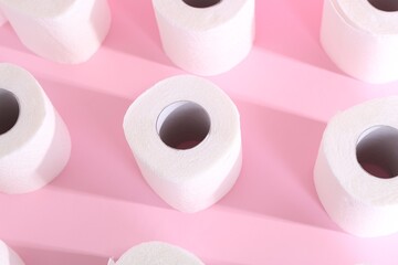 Many soft toilet paper rolls on pink background, above view