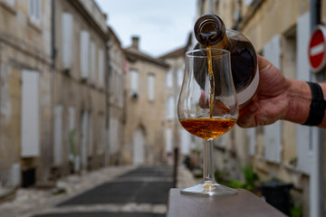 Tasting of cognac alcohol drink and view on old streets and houses in town Cognac, Grand Champagne, Charente, strong spirits distillation industry, France - obrazy, fototapety, plakaty