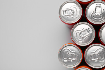 Energy drink in cans on grey background, top view. Space for text