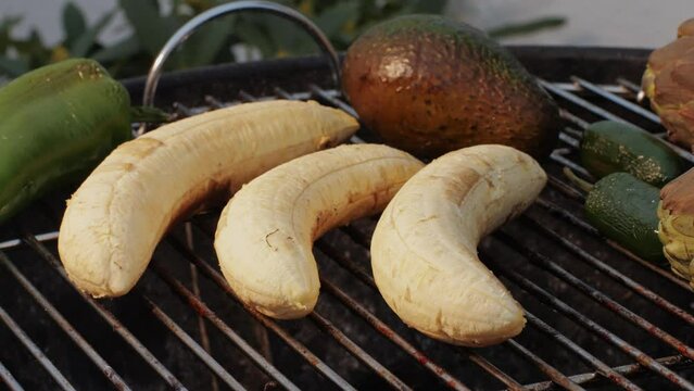 Grilled Banana on fire, latin american vegan grill with avocado and pepper, thai or Ecuadorian Street food. African traditional food on grill. 