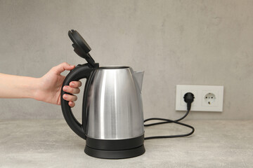 Woman with electric kettle in kitchen, closeup