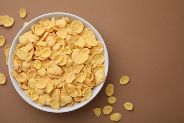 Breakfast cereal. Tasty corn flakes in bowl on brown table, top view. Space for text