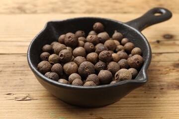 Dry allspice berries (Jamaica pepper) in dish on wooden table, closeup