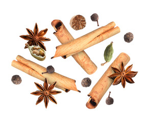 Cinnamon sticks and other aromatic spices falling on white background