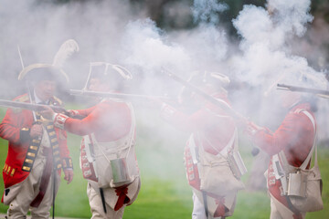 Reenactors portraying British soldiers fire their weapons during the revolution war of the...