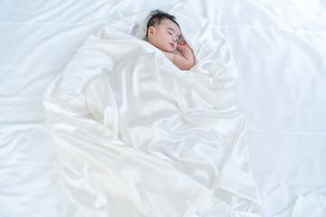 白い布に包まれて寝る赤ちゃん